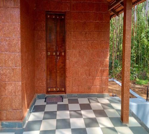 an empty room with a tile floor and a door at Stillwater Homestay in Chikmagalūr