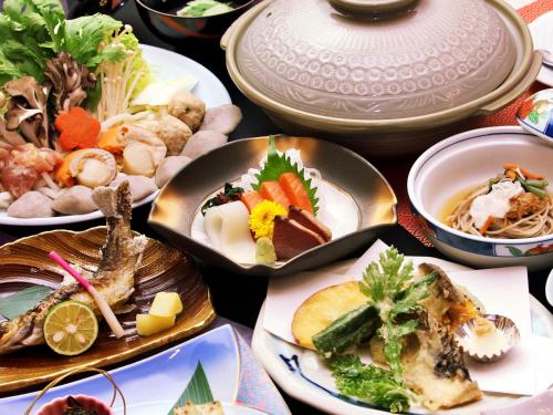 Kidoike Onsen Hotel في يامانوتشي: طاولة مليئة بأطباق الطعام وأوعية الطعام