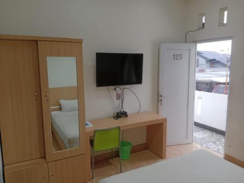 Zimmer mit einem Schreibtisch, einem TV und einem Spiegel in der Unterkunft Macan Kumbang Residence in Palembang