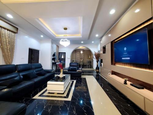 a living room with a large tv and black leather furniture at 3 bedrooms with Modern Amenities in Abeokuta