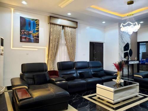 a living room with black leather furniture and a chandelier at 3 bedrooms with Modern Amenities in Abeokuta