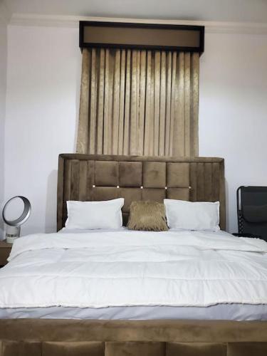a bedroom with a large bed with a wooden headboard at 3 bedrooms with Modern Amenities in Abeokuta