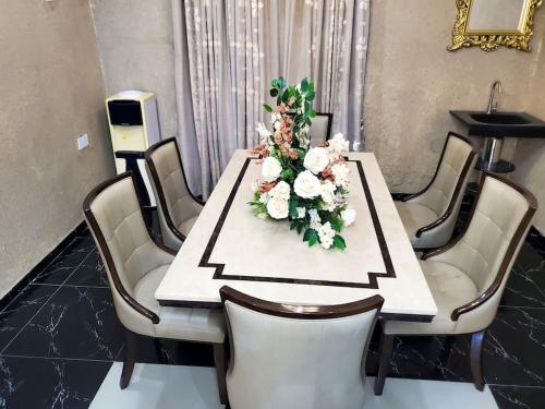 a dining room table with a flower arrangement on it at 3 bedrooms with Modern Amenities in Abeokuta