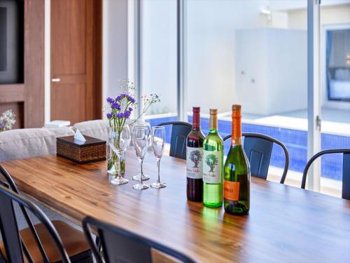 a wooden table with wine bottles and glasses on it at The Pool & Sauna Villa MOTOBU in Motobu