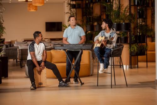 a group of three men sitting around a keyboard at Ocean's Creek Beach Hotel in Balaclava