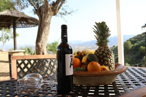 una botella de vino en una mesa con un bol de fruta en Chalet with private jacuzzi -Mi Dushi, en Tolox