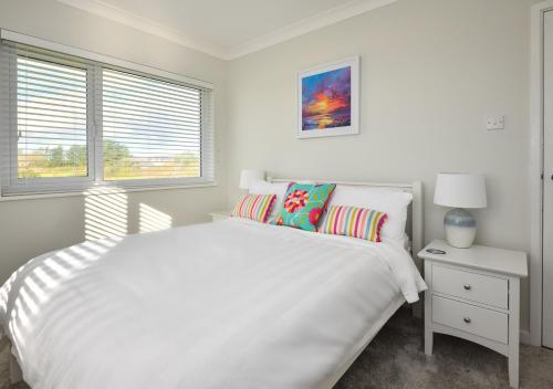 Un dormitorio blanco con una cama blanca y una ventana en Maes Coch, en Abersoch