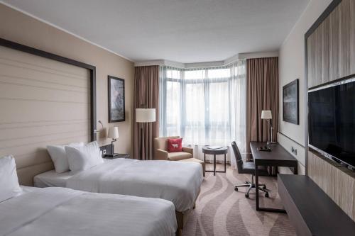 um quarto de hotel com duas camas e uma secretária em Munich Airport Marriott Hotel em Freising