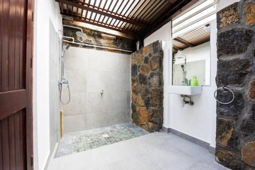 ein Bad mit einer Dusche und einem Waschbecken in der Unterkunft Quaint Beach Villa in a fishing village in Grand-Gaube