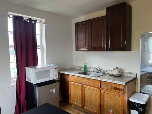 a small kitchen with a sink and a microwave at A bedroom with a shared full bathroom in Philadelphia