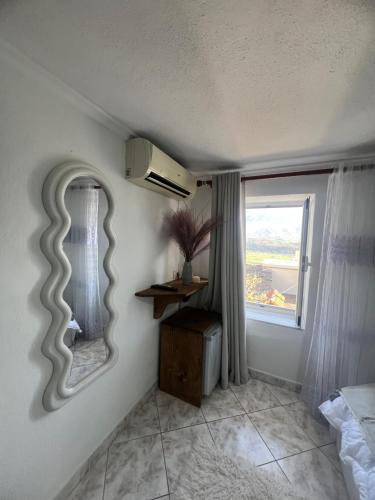 a bedroom with a mirror on the wall and a window at Himalayas in Gjirokastër