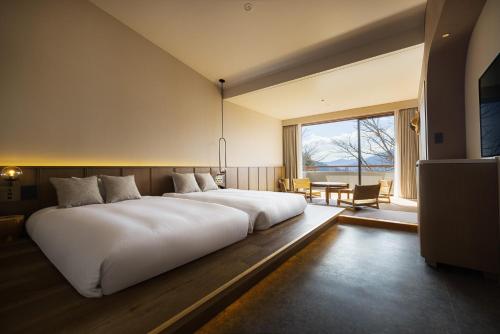 a large white bed in a room with a large window at nol hakone myojindai in Hakone