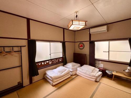 two beds in a room with three windows at Guesthouse KOBE YAMATOMUSUBI in Kobe