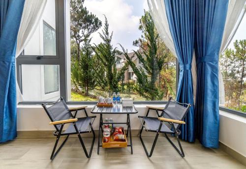 einen Tisch und Stühle in einem Zimmer mit einem großen Fenster in der Unterkunft Love Hill Resort in Da Lat