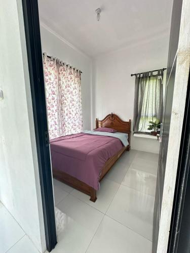 a bedroom with a bed with purple sheets and a window at Abimanyu Guesthouse in Sumedang