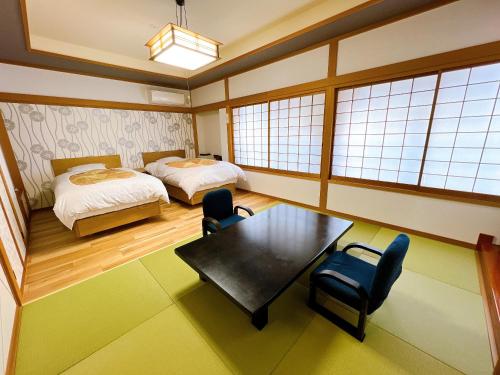 静岡市にあるKOUBOUNOYU IKONASOUのベッド、テーブル、椅子が備わる客室です。