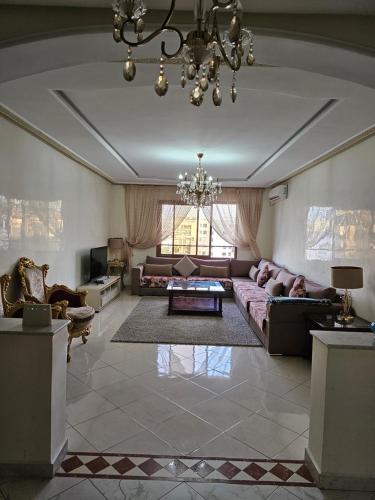 ein großes Wohnzimmer mit einem Sofa und einem Kronleuchter in der Unterkunft la perle du tanger R in Tangier
