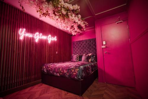 Cette chambre rose comprend un lit et un panneau de néon. dans l'établissement The Ultimate Hen Suite with Bar & Makeup Room, à Manchester