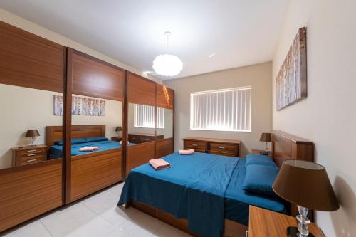 - une chambre avec un lit bleu et des placards en bois dans l'établissement Modern 2 Bedroom Apartment 2 minutes to Seafront, à San Pawl il-Baħar