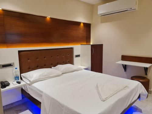 1 dormitorio con 1 cama blanca grande y cabecero de madera en Hotel Sannidhi, en Vijayawāda