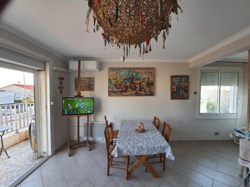 une salle à manger avec une table et une télévision dans l'établissement Palavas les flots vue mer, à Palavas-les-Flots