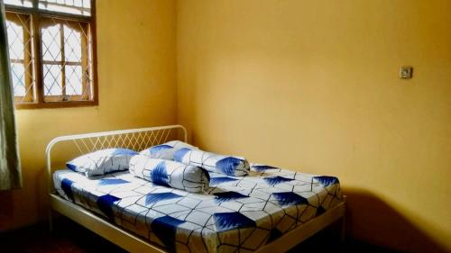 uma cama com almofadas azuis e brancas num quarto em Sewa Rumah 4 Kamar Tidur em Bandung