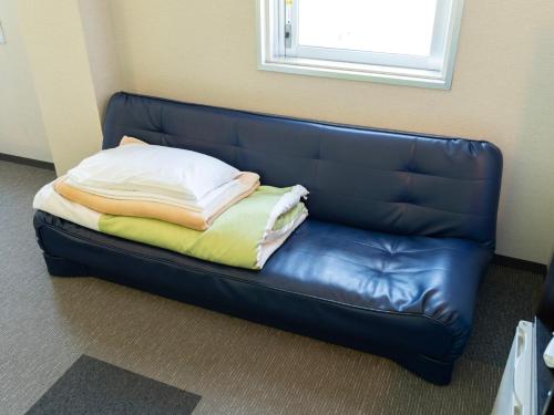 a leather couch in a room with a pillow on it at Super Hotel Tozai line Ichikawa Myoden Ekimae in Ichikawa