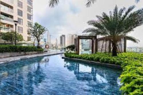 a pool of water with a palm tree and a building at Delightful Apartment - Masteri Millennium - FREE Infinity Pool in Ho Chi Minh City