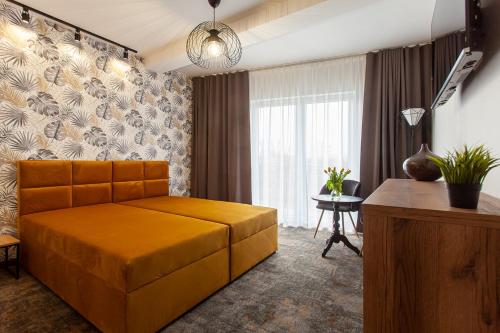 a bedroom with a large orange bed and a table at Bursztynowa Przystań in Grzybowo