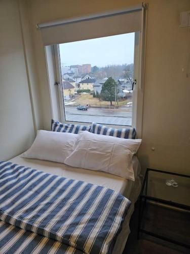 a bed in a room with a large window at skyline flat with free parking in Lorenskog