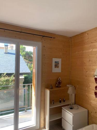 Cette chambre dispose de murs en bois, d'une fenêtre et d'une lampe. dans l'établissement A 5 minutes a pied du centre , Appartement T2 Font-Romeu, à Font-Romeu-Odeillo-Via