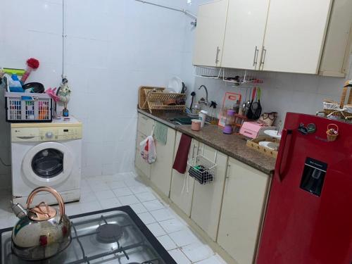 una cucina con frigorifero rosso e lavatrice di The Hostel a Dubai