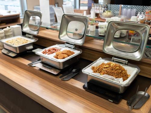 a buffet with trays of food on a counter at Super Hotel Tozai line Ichikawa Myoden Ekimae in Ichikawa