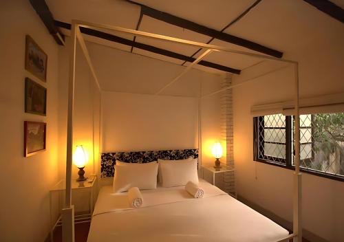 a bedroom with a white bed with two lamps at Lost & Found - Colombo in Colombo