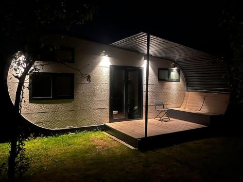 een huis 's nachts met een stoel op een terras bij Tinyhouse Friesland 