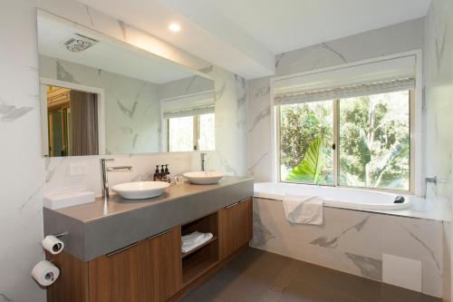uma casa de banho com 2 lavatórios e um espelho grande em Songbirds Rainforest Retreat em Mount Tamborine
