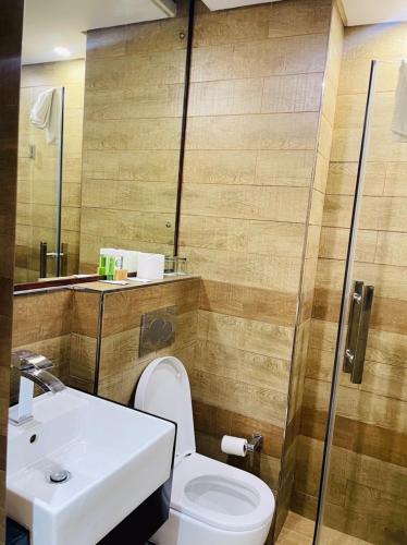 a bathroom with a toilet and a sink and a shower at Aquarian Tide Hotel in Gaborone