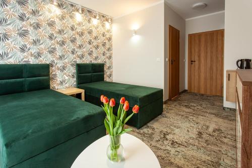 a living room with a green couch and a table with flowers at Bursztynowa Przystań in Grzybowo