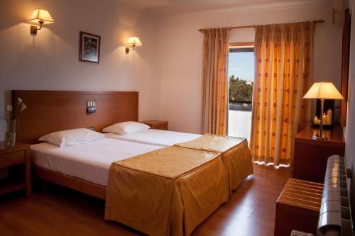 a bedroom with a large bed and a large window at Hotel Santa Mafalda in Fátima
