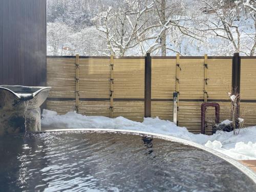 a swimming pool covered in snow with a fence at Keiryuso Siorie in Matsumoto