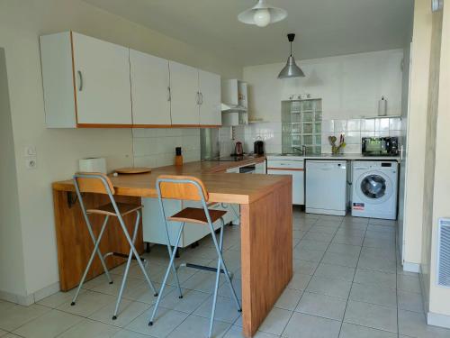 cocina con mesa de madera y 2 sillas en Maison entière - 3 chambres/3 salles de douche en Montigny-le-Bretonneux