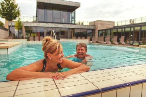 a man and a woman in a swimming pool at Apartman Hotel in Bük