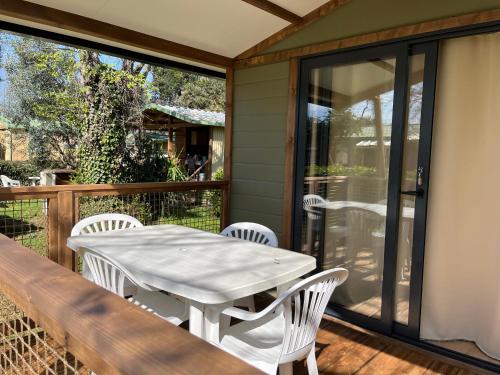 a white table and chairs on the deck of a house at Ri-Veu corse dans camping marina di sorbo in Sorbo-Ocagnano