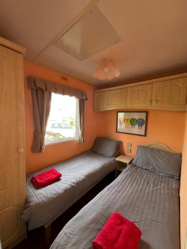 2 Betten in einem kleinen Zimmer mit Fenster in der Unterkunft Holiday Home by the sea in Aberystwyth