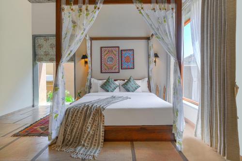 SaffronStays Moringa Wishing Tree في أودايبور: غرفة نوم مع سرير مظلة في غرفة مع نافذة