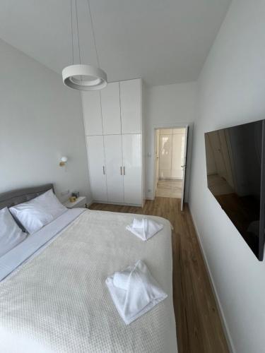 a bedroom with a white bed with two towels on it at Apartament Dziwnów White & Gold in Dziwnów