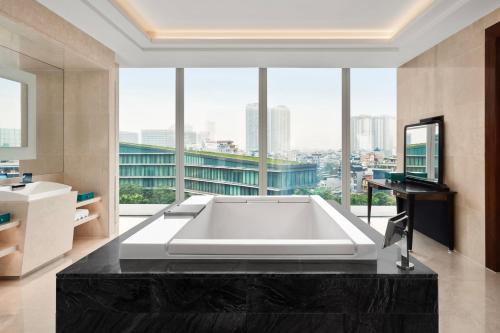 a large white bath tub in a bathroom with a large window at JW Marriott Hotel Hanoi in Hanoi