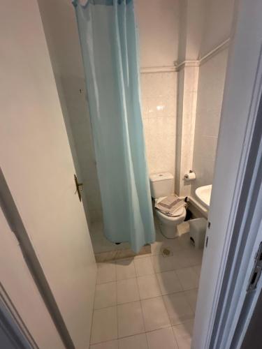 a bathroom with a toilet and a blue shower curtain at Pansion Angela in Skiathos Town