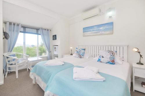 two beds in a white room with a window at Mermaid Guest House in Struisbaai