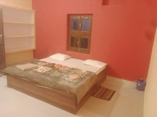 łóżko w czerwonym pokoju z oknem w obiekcie Aanand Bhwan dharmshala ayodhya w mieście Ayodhya